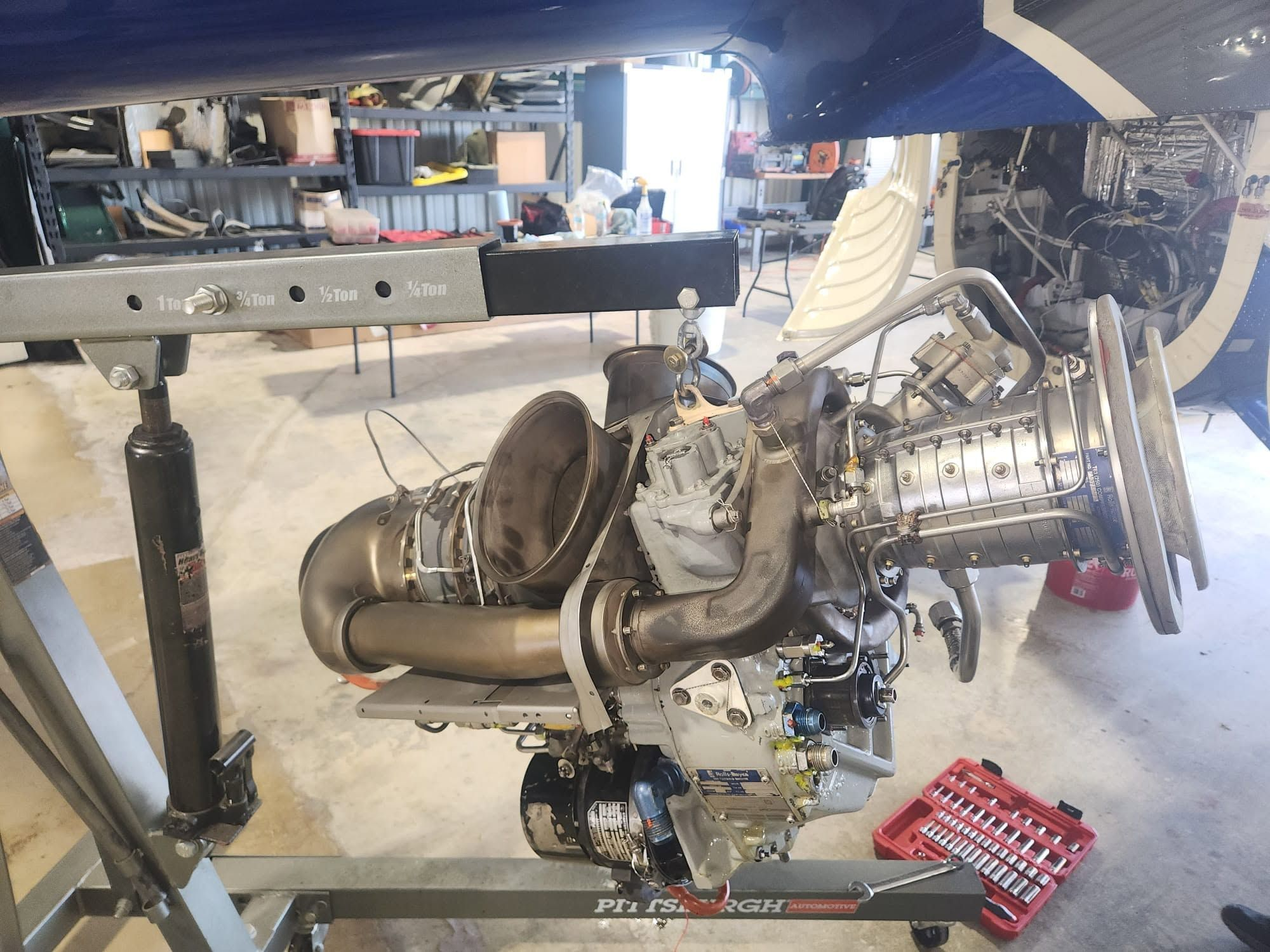 Rolls-Royce 250 turboshaft engine suspended from an engine hoist during removal or installation on a helicopter.