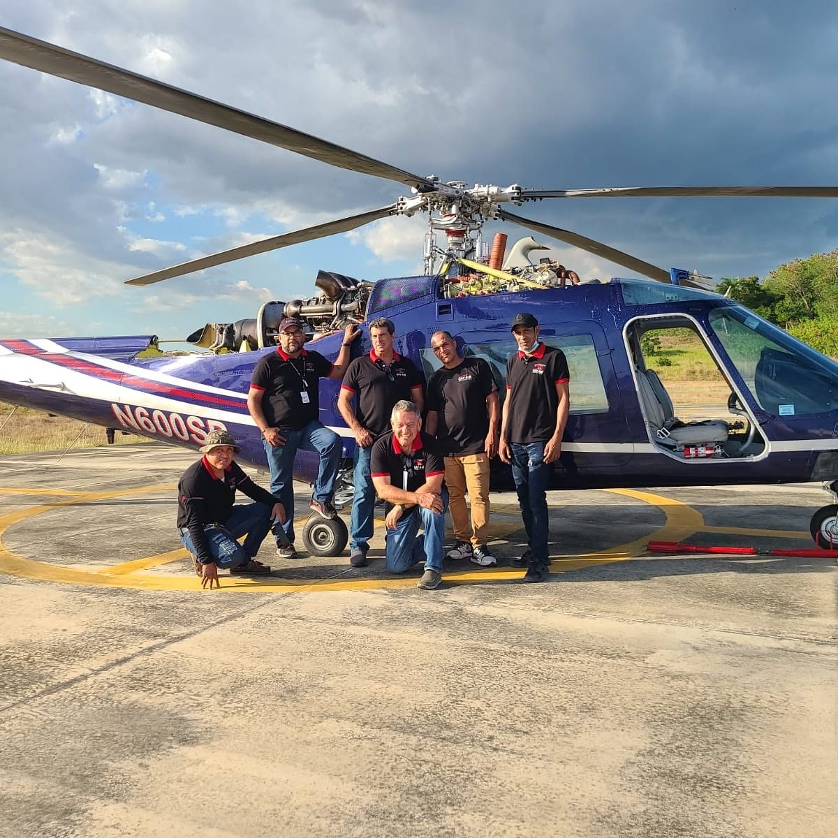 The CAV AIR HELICOPTERS maintenance team beside a helicopter with its engine cowlings open