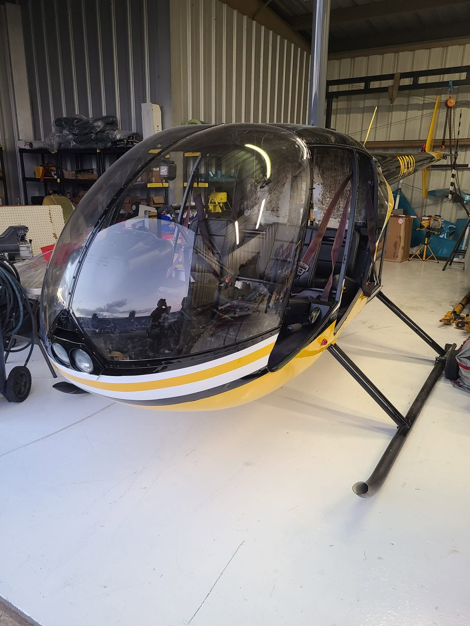 Helicopter with newly completed black, yellow and white paint, its cabin and windshield unmasked in the hangar.